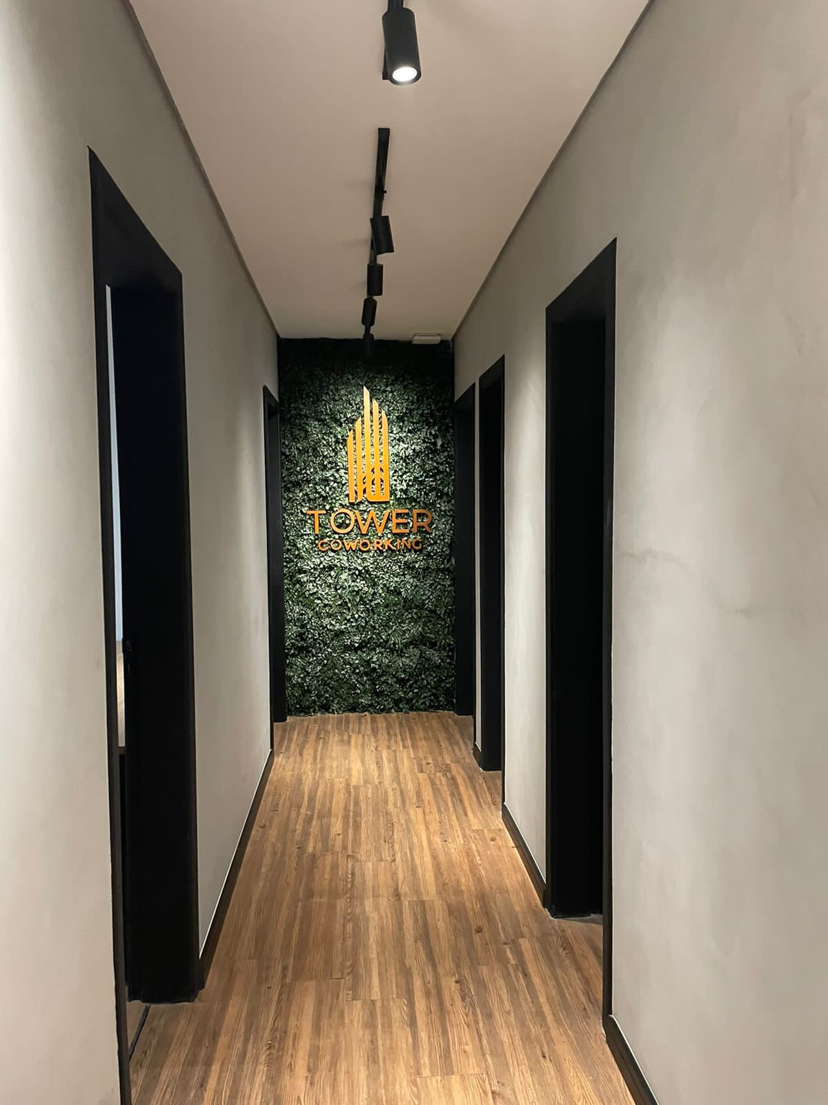 Corredor do Tower Coworking com o logo dourado no jardim vertical em São Caetano do Sul